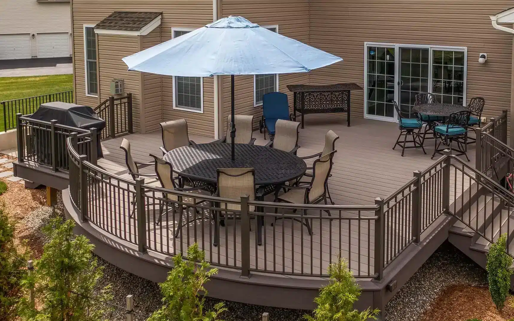 deck contractor in bridgewater nj photo of Spacious backyard deck with cushioned seating, dining area, and a large umbrella.