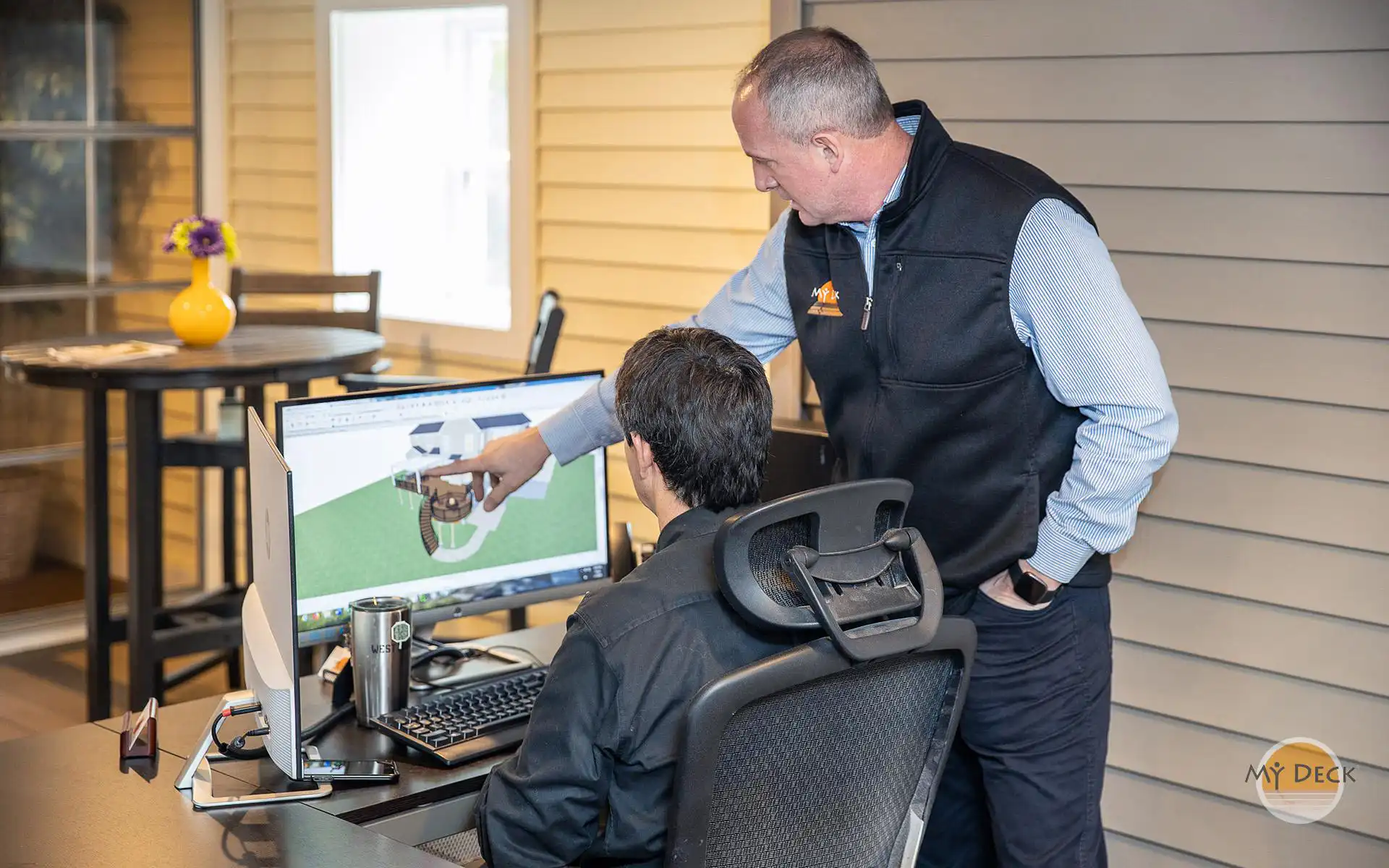 Photo of a My Deck designer showing a homeowner how the 3D design services work at a computer 