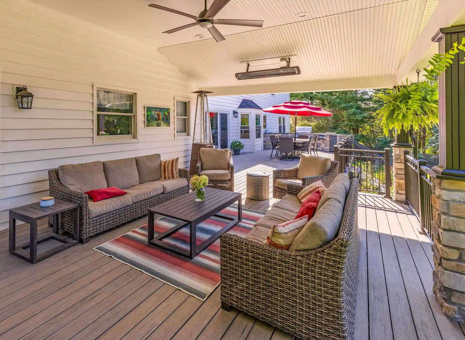 Photo of a composite deck that runs the length of the house with a covered deck part, complete with ceiling fans and heaters, and an open deck area. This was built by My Deck, decking contractors in Hillsborough, NJ, and Central New Jersey.