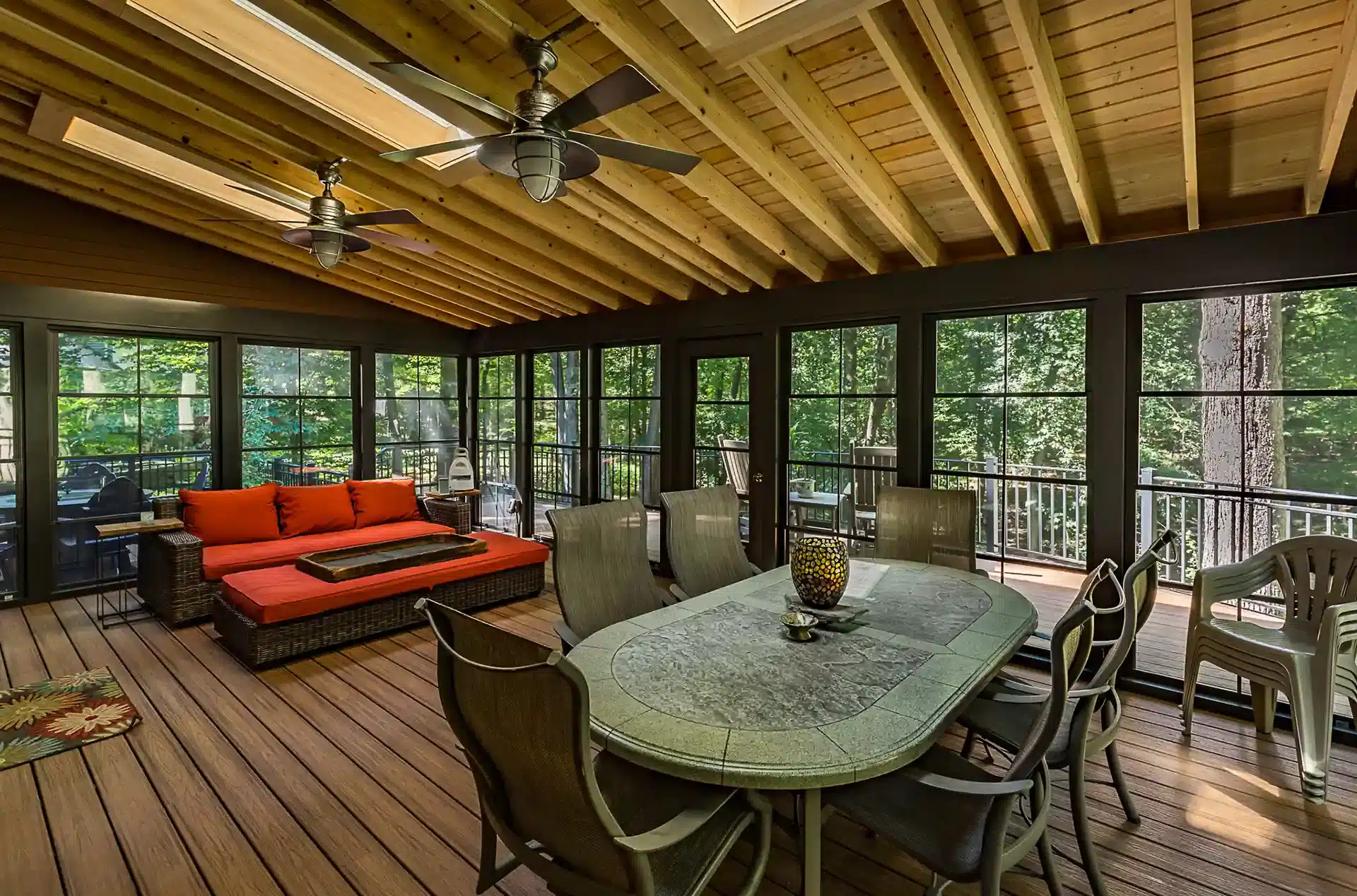 Photo of a covered porch/outdoor room with ceiling fans, sunlights, and furniture.
