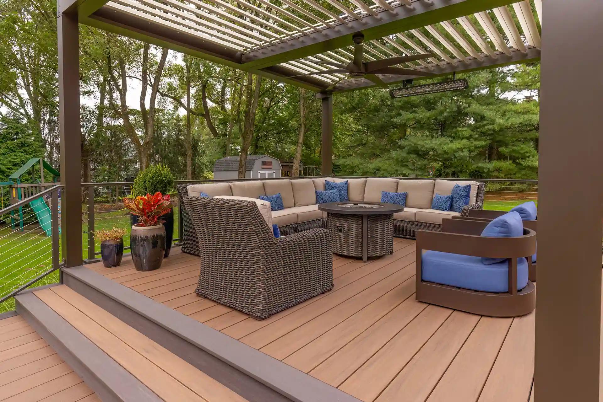 Photo of a multi-level deck made with TimberTech by AZEK advanced PVC deck boards. It has a louvered roof pergola and outdoor furniture. 