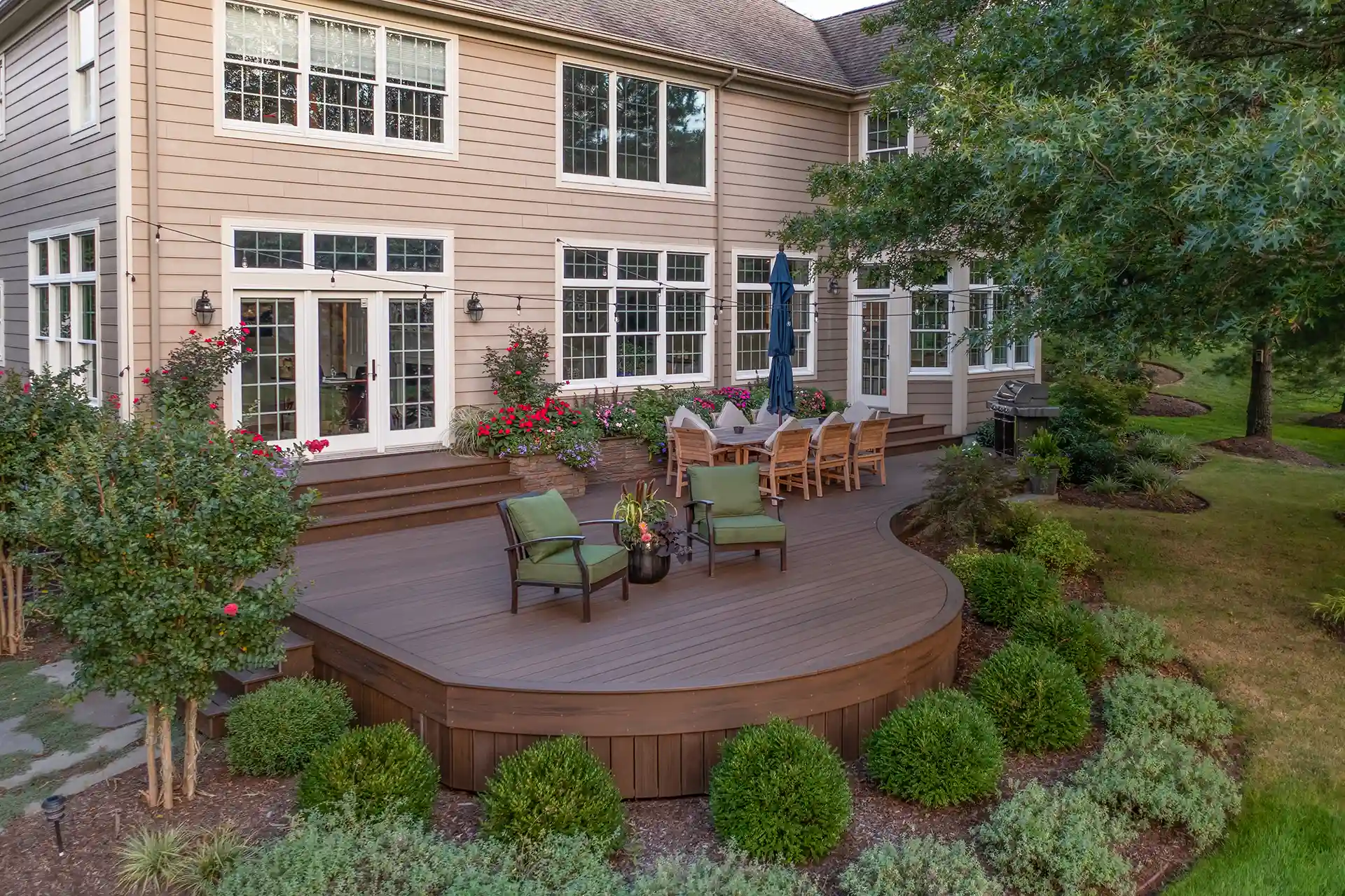deck design with planters Photo of Curved brown deck with outdoor seating, grill, creative planter boxes, and a two-story house.