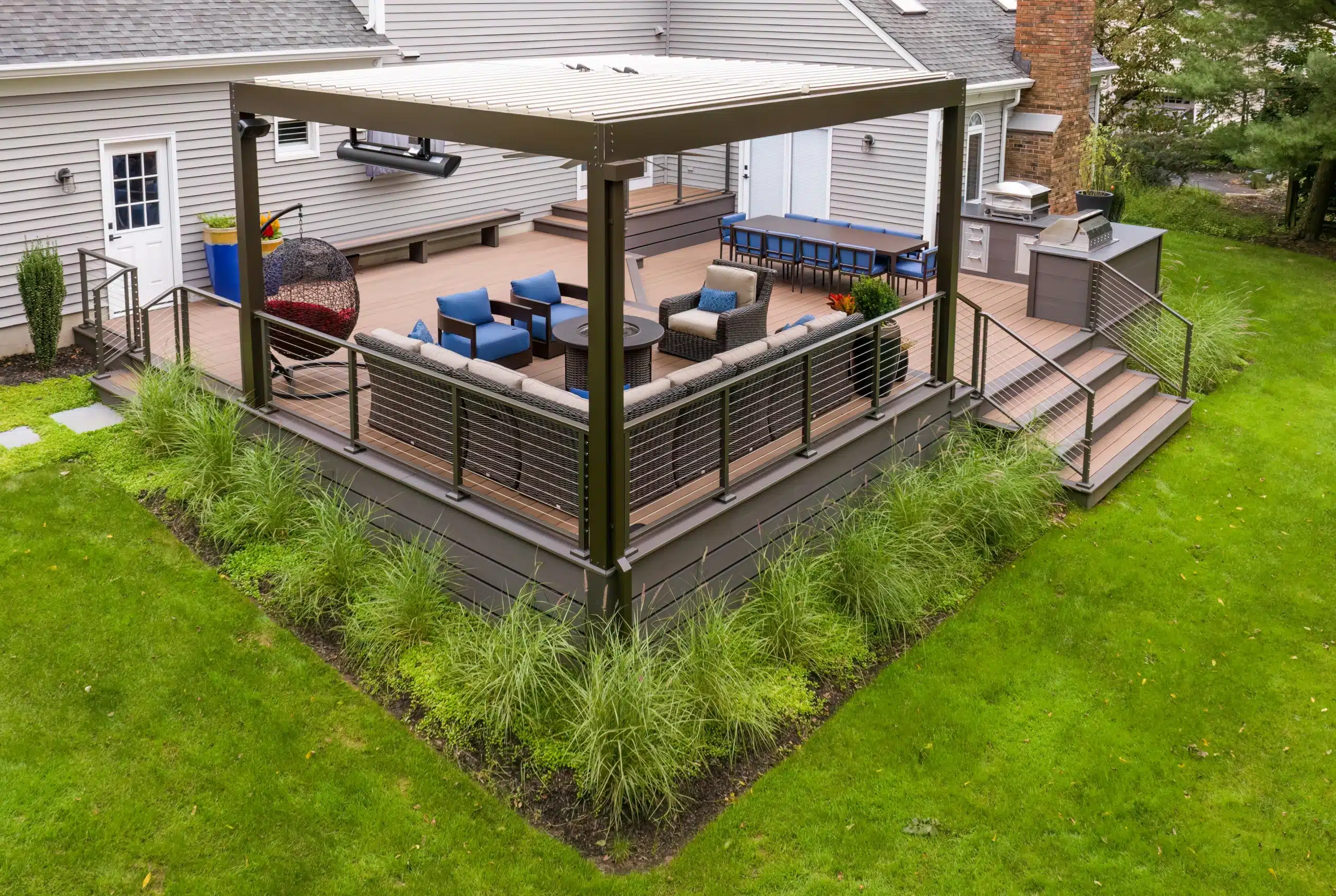 azek decking installation in central new jersey Photo of an AZEK deck with pergola, outdoor furniture, fire pit, built-in benches, and an outdoor kitchen.