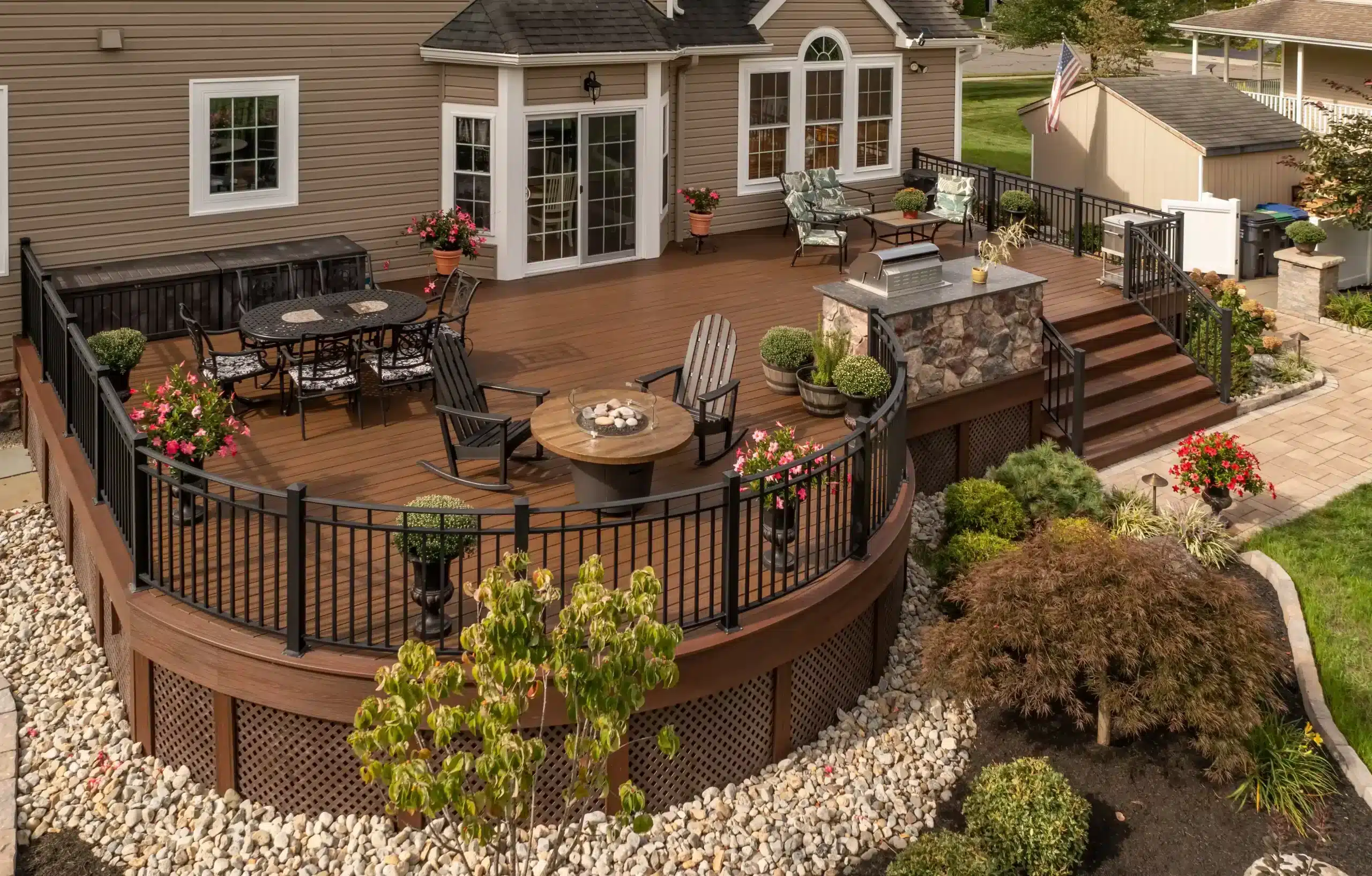 deck stair designs in central new jersey Photo of a curved deck with outdoor furniture, an outdoor kitchen, and deck steps and railing.